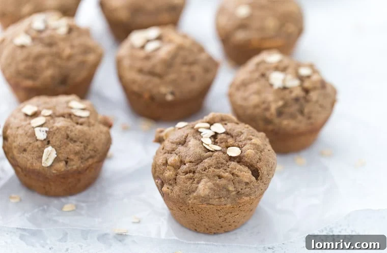 Close-up of several banana nut muffins on wax paper against a white background.