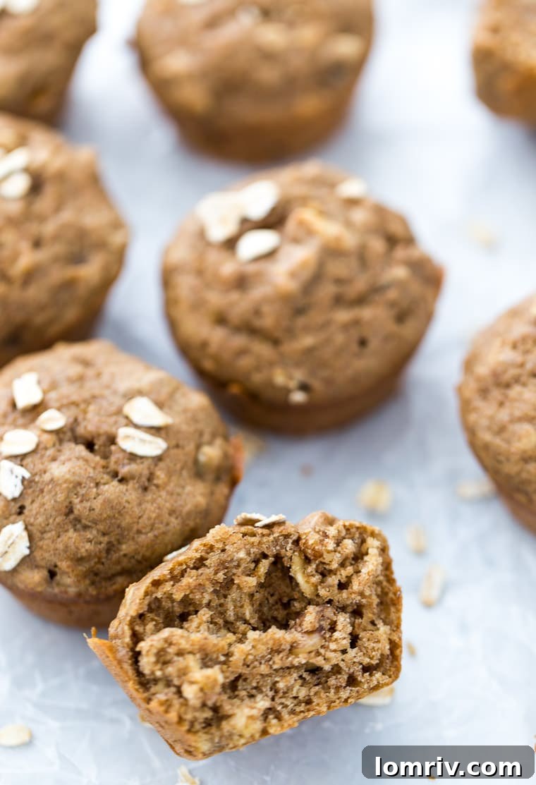 A banana nut muffin cut in half, showcasing its moist interior, with other muffins in the background.
