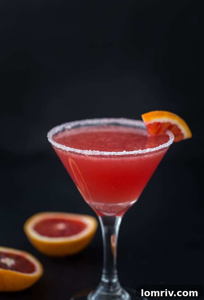 A vibrant blood orange vanilla martini, elegantly garnished, perfect for unwinding after a long week.
