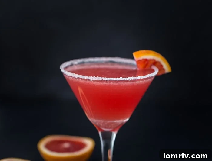 A close-up of a Blood Orange Vanilla Martini, showcasing its vibrant color and elegant garnish, ready to be enjoyed.