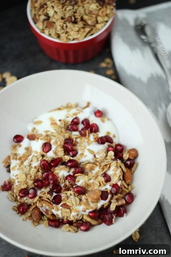 Serving homemade Coconut Almond Granola with Greek yogurt and fresh pomegranate seeds.