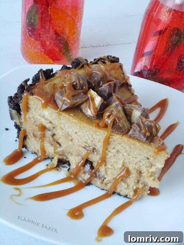 Decadent Snickers Peanut Butter Cheesecake with chocolate drizzle and candy pieces