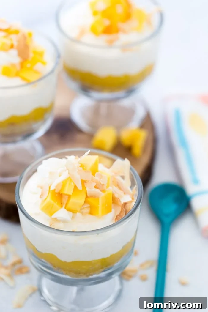 Beautifully layered Coconut Mango Mousse cups garnished with fresh mango slices and toasted coconut, ready to be enjoyed as a refreshing tropical dessert