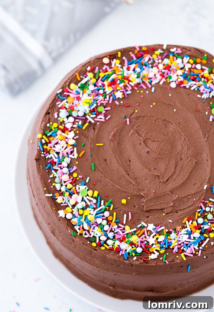A slice of classic yellow cake revealing its moist crumb, topped with generous chocolate frosting.