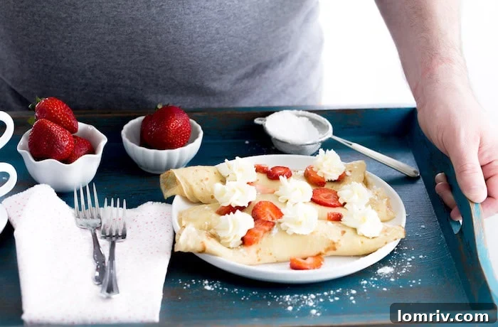 Prepared strawberry mascarpone crepes, rolled and garnished with extra cream and berries, ready to be served.