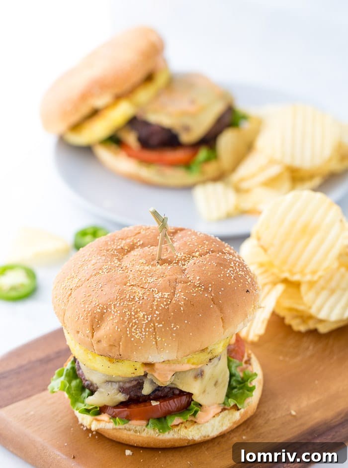 Juicy pineapple jalapeno burgers topped with pepper jack cheese, creamy chipotle mayo, sweet grilled pineapple, and smoky grilled jalapenos, ready for a flavorful summer meal.