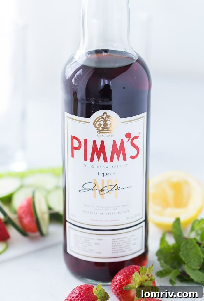 A close-up shot of the Classic Pimm's Cup cocktail, showcasing its vibrant red hue and abundant fresh fruit garnishes of strawberries, cucumber, and mint.