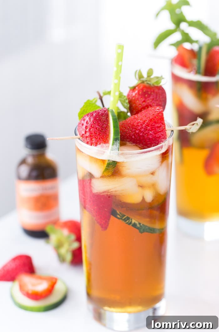 A refreshing Classic Pimm's Cup cocktail, enhanced with orange blossom water, fresh strawberries, and cucumber slices, served outdoors.