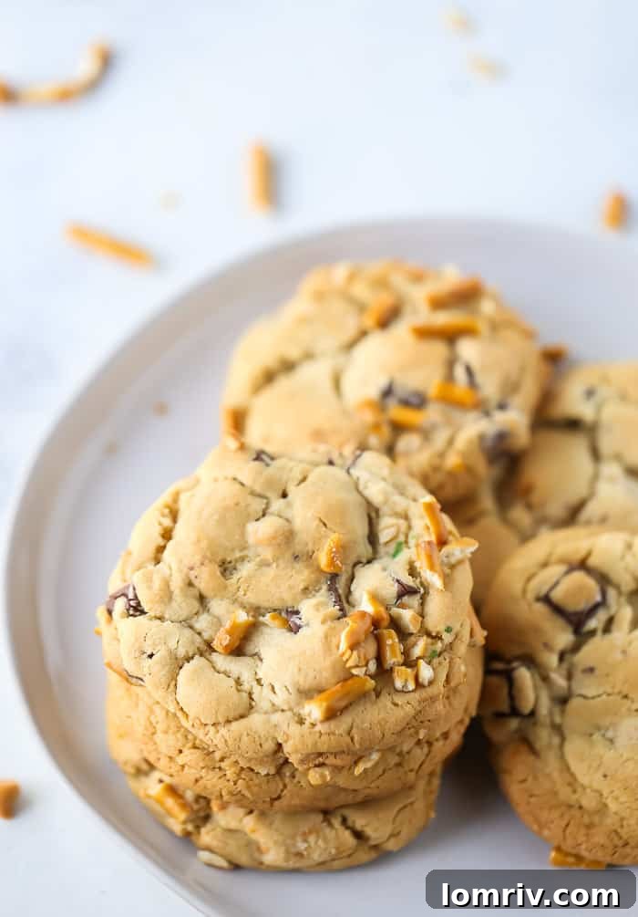 A closer look at a plate of freshly baked Butterscotch Pretzel Chocolate Chip Cookies, highlighting their golden edges and varied textures.