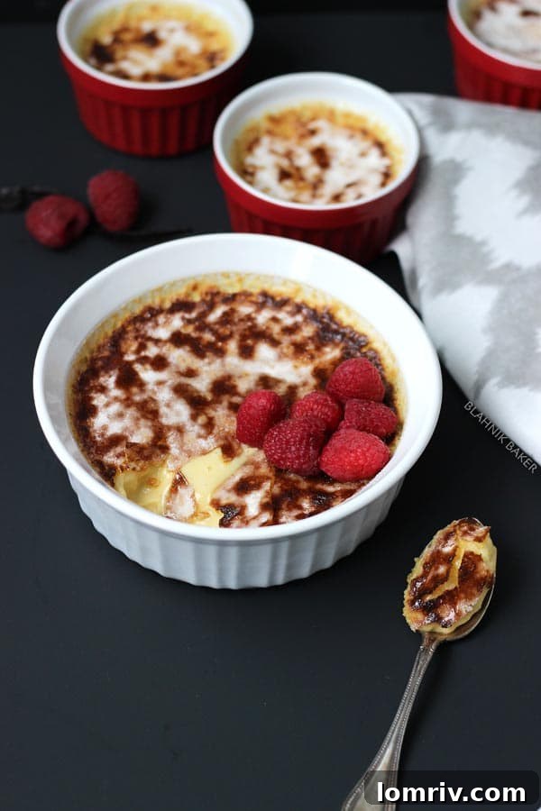 Elegant Vanilla Bean Crème Brûlée with a perfect caramelized top, garnished with fresh raspberries