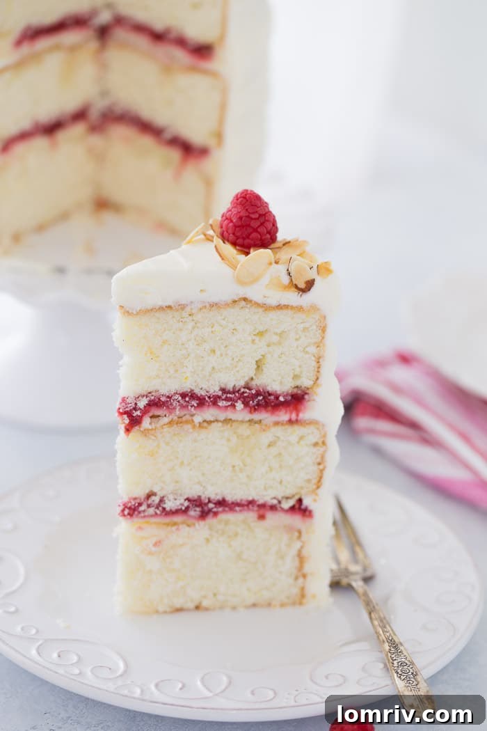 Close-up of a slice of lemon raspberry cake, showing distinct layers of cake, compote, and mascarpone filling.