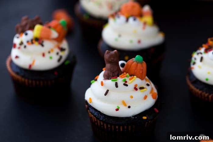 Moist chocolate cupcakes topped with white vanilla buttercream and colorful Halloween candies, perfect for an easy holiday treat.