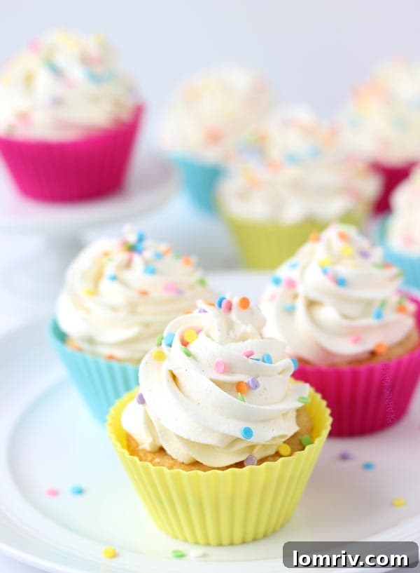 A tray of vanilla cupcakes baked in colorful silicone baking cups