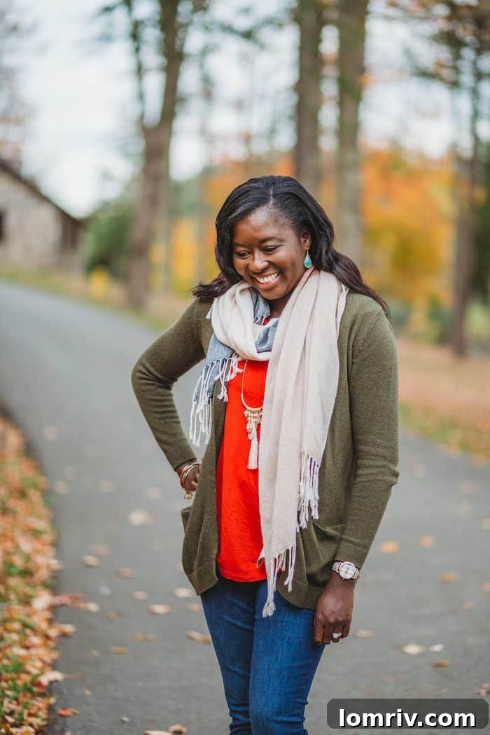 A woman models a stylish green open-front cozy fall sweater paired with jeans, a scarf, and boots, showcasing a perfect autumn outfit.