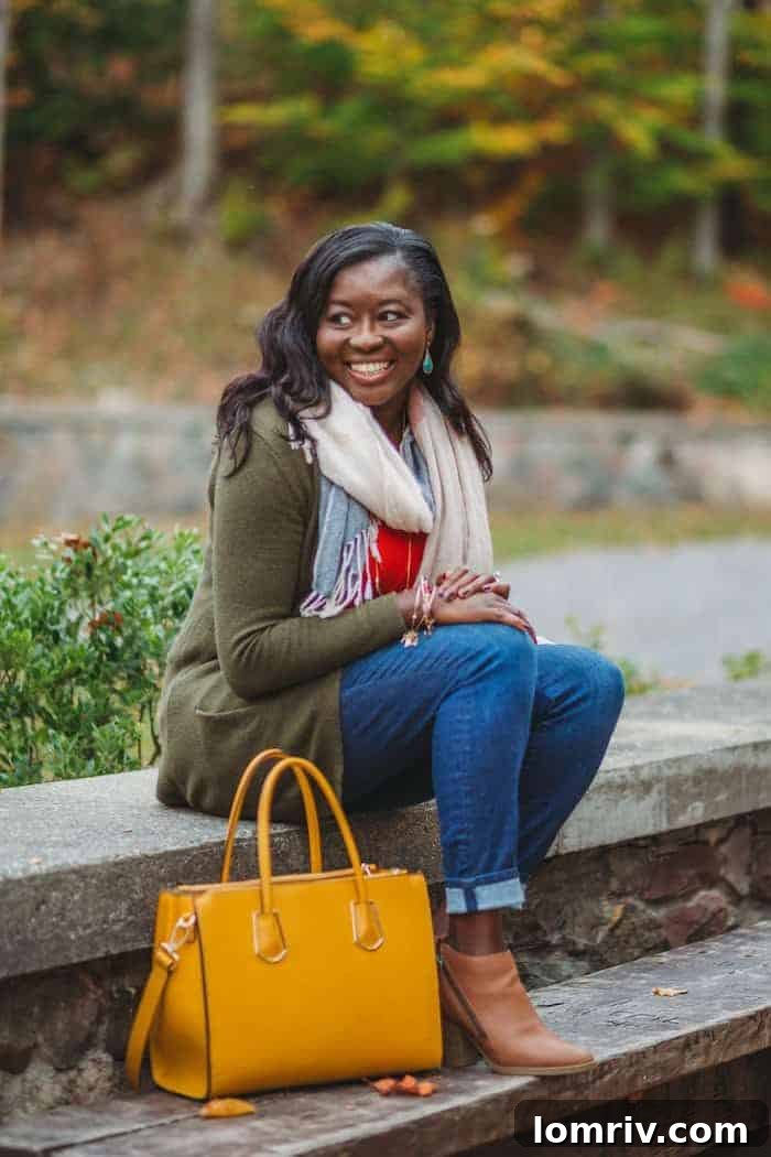 A close-up detail of a women's outfit, featuring a textured knit sweater, a glimpse of blue jeans, and a stylish patterned scarf, embodying casual fall comfort.