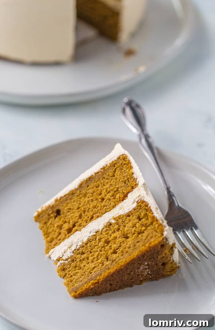 Close-up of a slice of moist spiced pumpkin cake with a generous layer of brown sugar Swiss meringue buttercream.