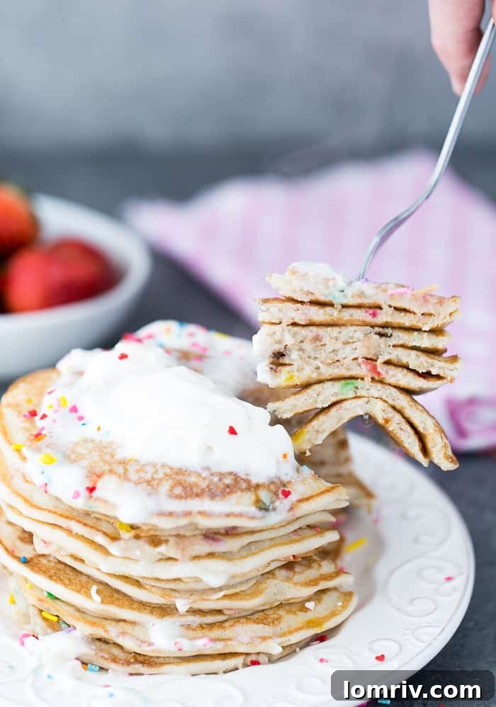 A close-up of a stack of Funfetti Buttermilk Pancakes, featuring a light and airy texture with visible sprinkles.