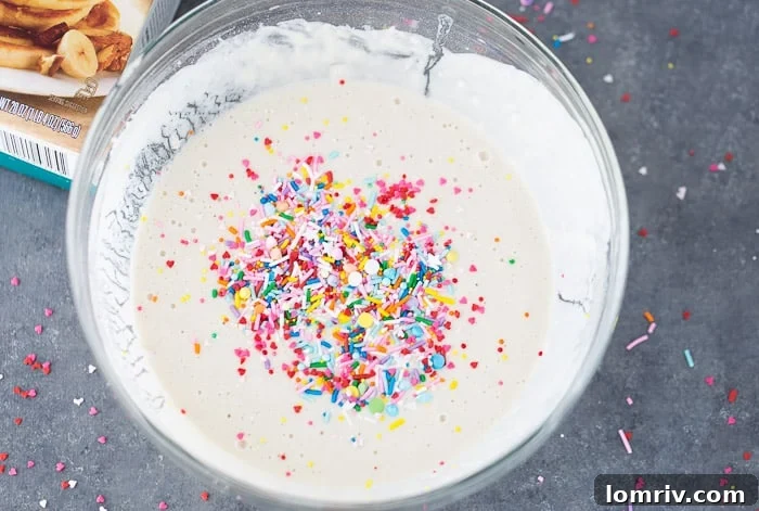A bowl of funfetti pancake batter, showcasing colorful sprinkles mixed throughout.