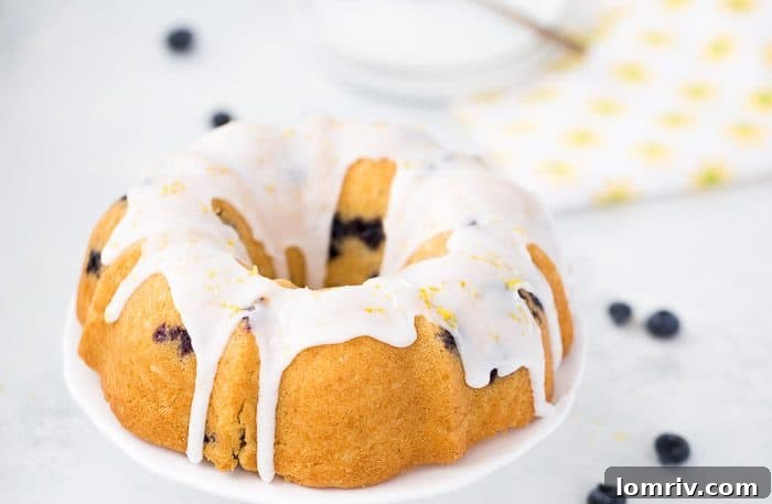 A slice of Blueberry Lemon Pound Cake with a generous drizzle of lemon glaze on a white plate.