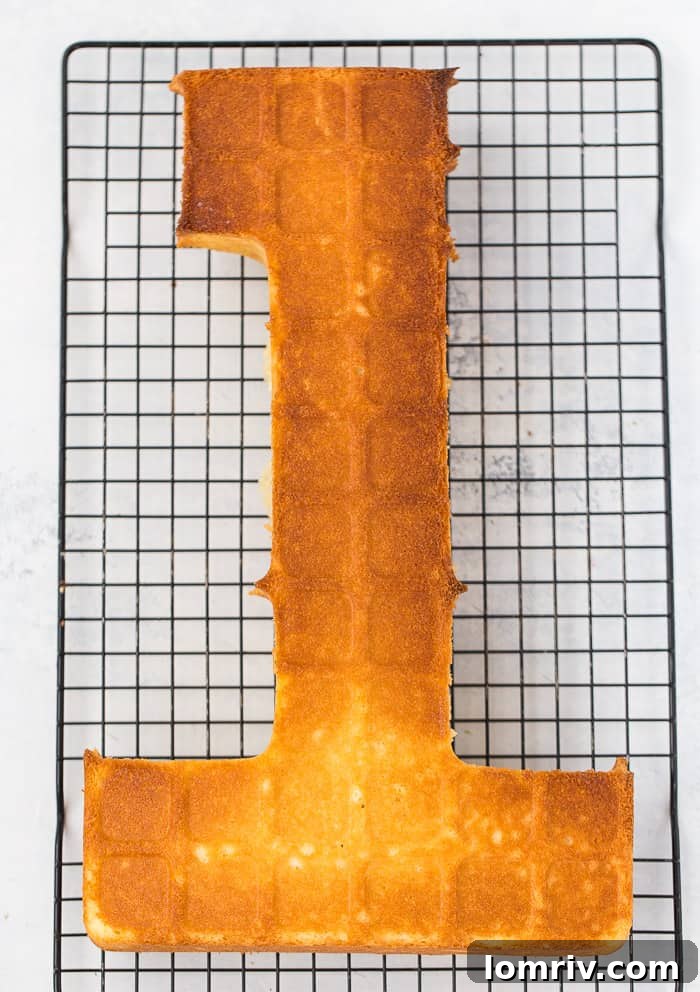 A baked cake layer being carefully removed from the number cake pan.