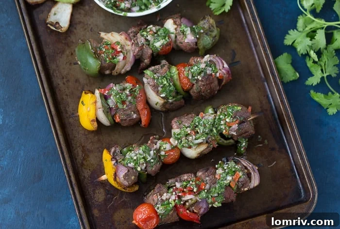 Close up of Cooked Beef Kebabs on a White Plate with Fresh Chimichurri Sauce