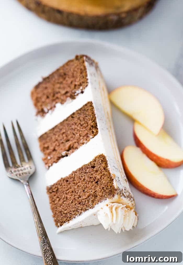 Full view of the layered apple spice cake, beautifully frosted with cinnamon buttercream and a generous caramel drizzle, ready to be served.