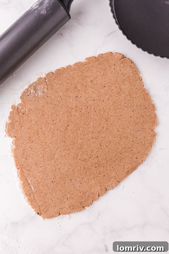 Pumpkin tart crust rolled out on a white surface. 