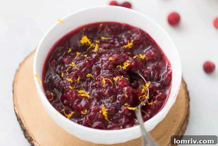 Homemade cranberry sauce served in a rustic bowl, garnished with rosemary