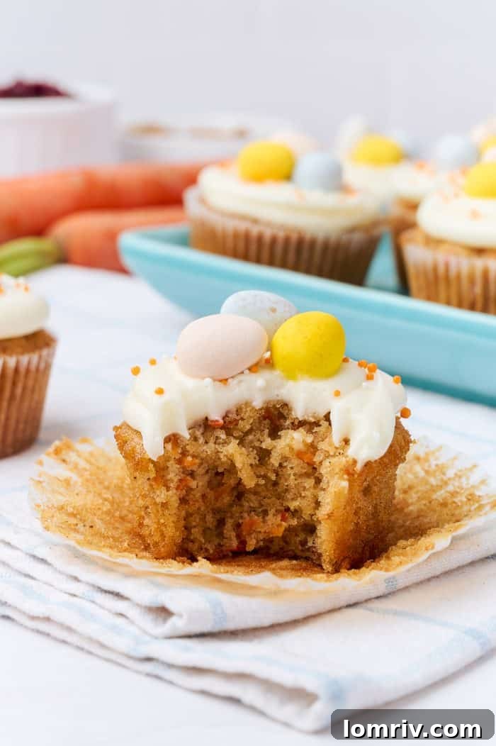 A carrot cake cupcake with a small bite taken from it, showing the moist interior.