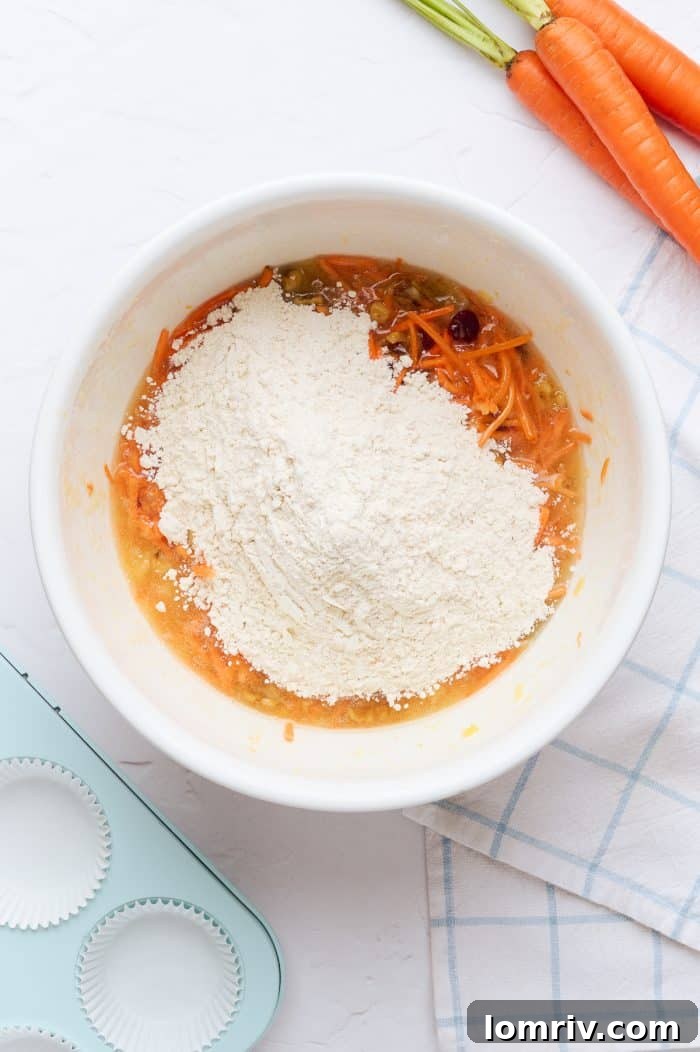 A white mixing bowl with flour added to the wet ingredients, halfway through mixing.