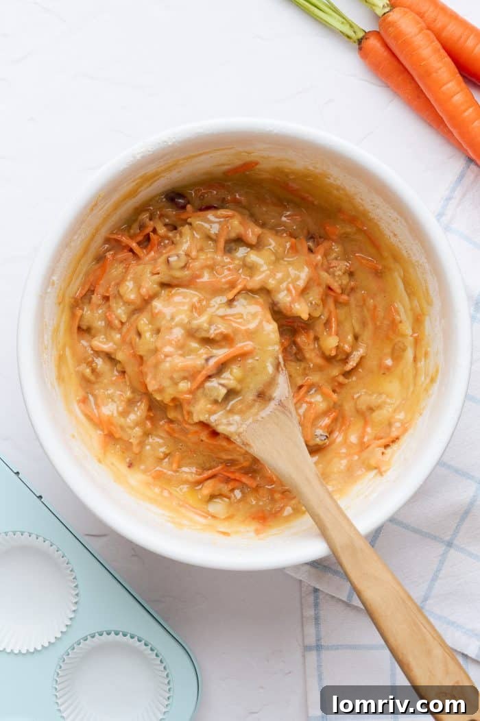 A white mixing bowl showcasing the perfectly combined carrot cake cupcake batter.