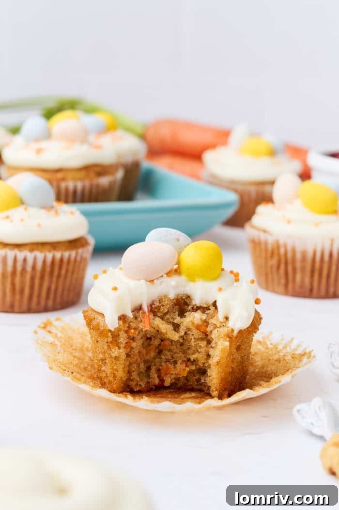 A carrot cake cupcake with a bite taken out, revealing its moist texture.