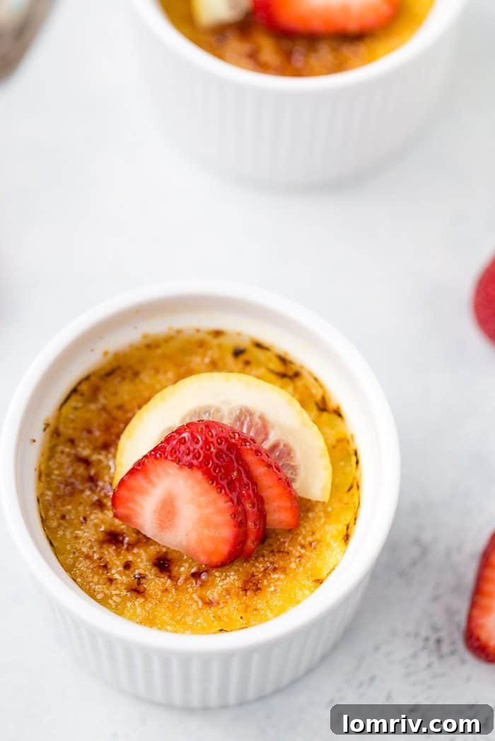 Four Lemon Creme Brulee ramekins arranged beautifully, garnished with fresh strawberries and mint.