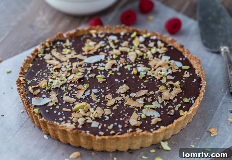 A rich and beautifully garnished Chocolate Raspberry Coconut Almond Tart, showcasing its gluten-free and vegan deliciousness on a serving plate.