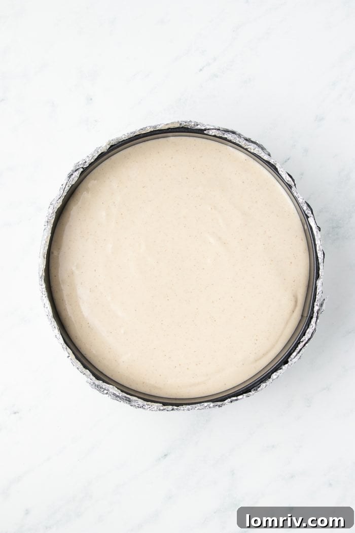 The cheesecake batter added to the cheesecake pan with the crust.