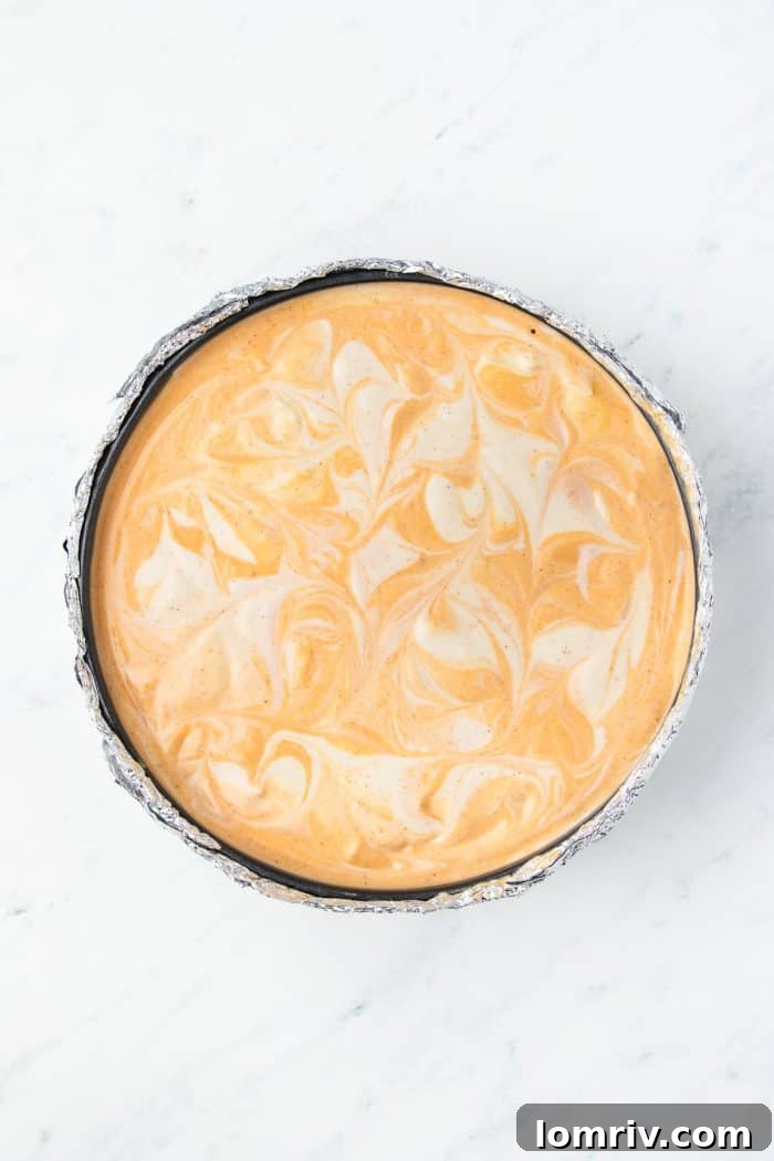 The pumpkin cheesecake batter portion has been added to the cheesecake pan and swirled.