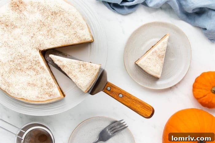 Two slices of pumpkin cheesecake. One slice is being removed from the cheesecake and the other slice is on a white plate.