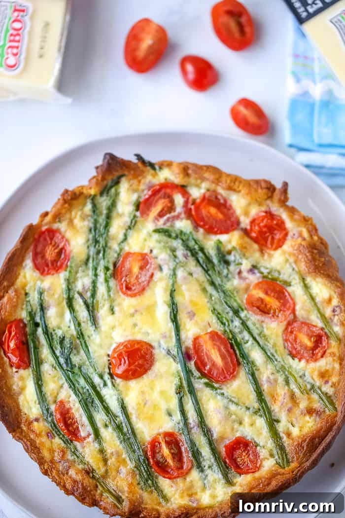 Delicious Easy Asparagus Cheese Tart on a wooden board with a slice removed, garnished with fresh herbs