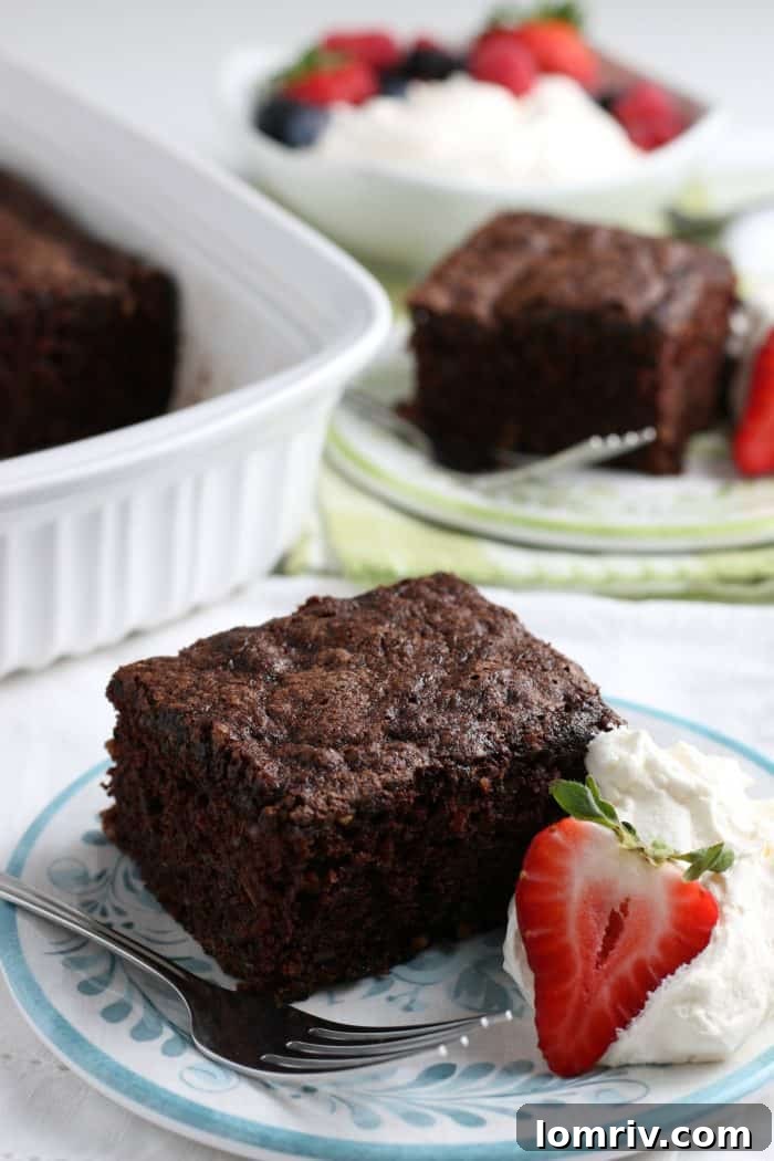 Moist Chocolate Zucchini Cake topped with fresh whipped cream, a perfect summer dessert.