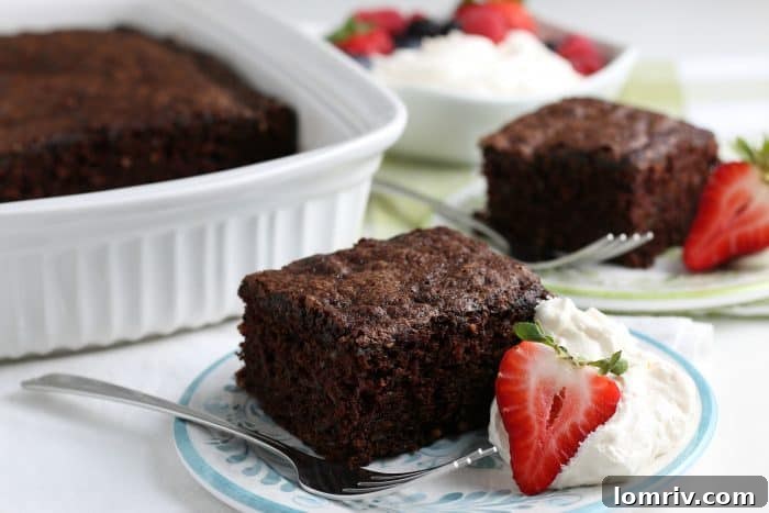 Slice of Chocolate Zucchini Cake with whipped cream, showing the moist interior.