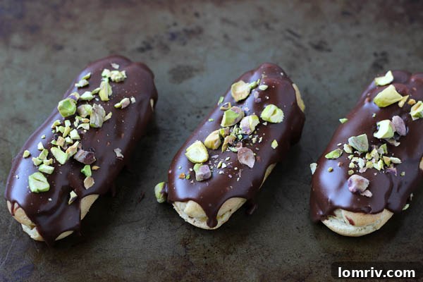 Two Chocolate Pistachio Éclairs on a white surface