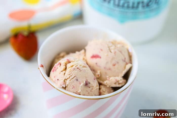 A close-up of vibrant homemade strawberry ice cream, showcasing its creamy texture and bits of fresh fruit.