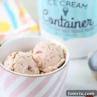 A bowl of Homemade Strawberry Ice Cream with fresh strawberries and mint garnish.