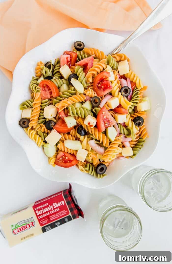 Close-up of a forkful of summer pasta salad with cheddar and vegetables, highlighting the texture and freshness
