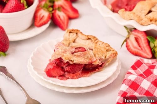 A slice of homemade strawberry pie on a plate, showcasing the vibrant filling and flaky crust.