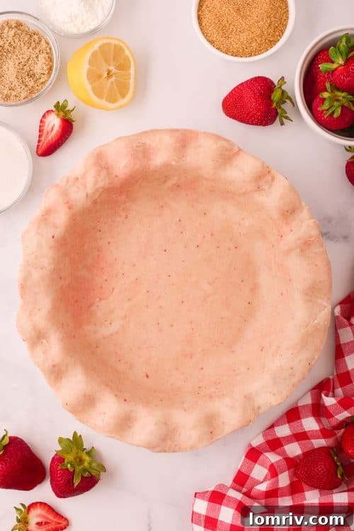 Homemade strawberry pie crust perfectly fitted into a pie plate, with decorative edges.