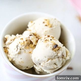 A bowl of Banana Walnut Cheesecake Ice Cream garnished with banana slices and walnuts.