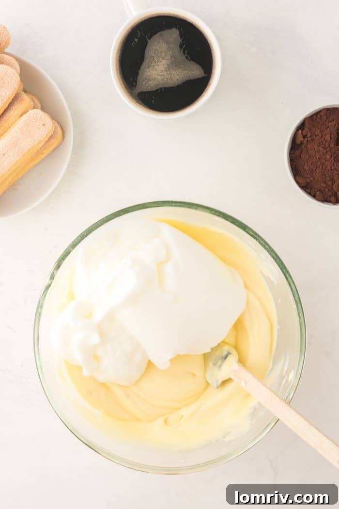 Gently folding whipped egg whites into the mascarpone mixture