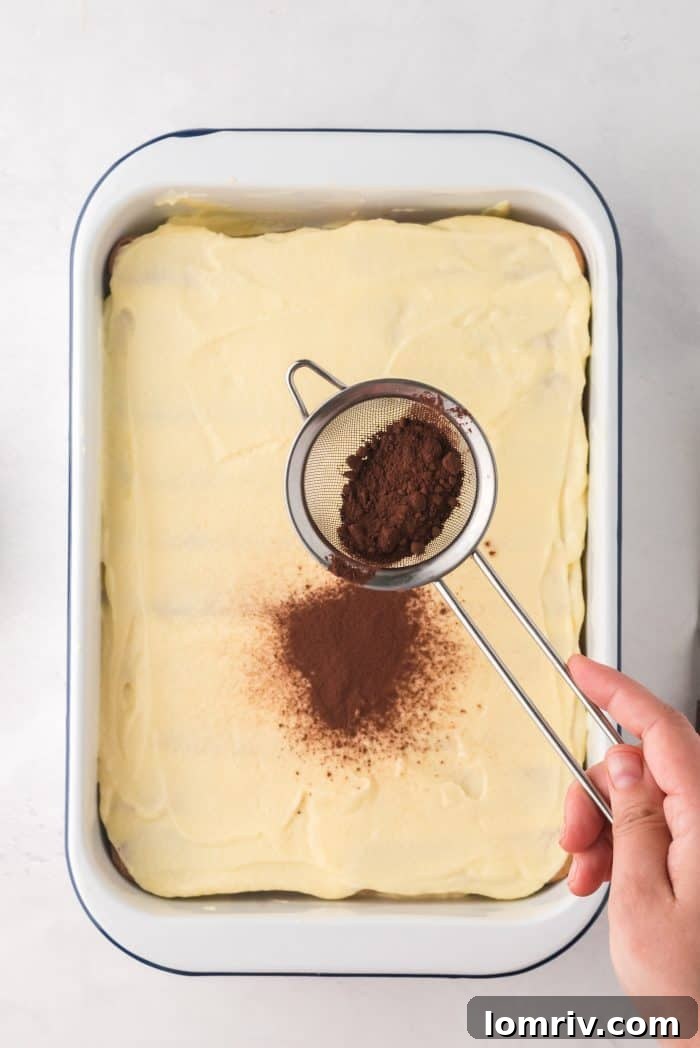 Dusting Tiramisu with cocoa powder before chilling