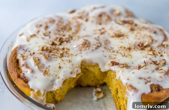A plate of two decadent Pumpkin Cinnamon Rolls with generous maple cream cheese frosting